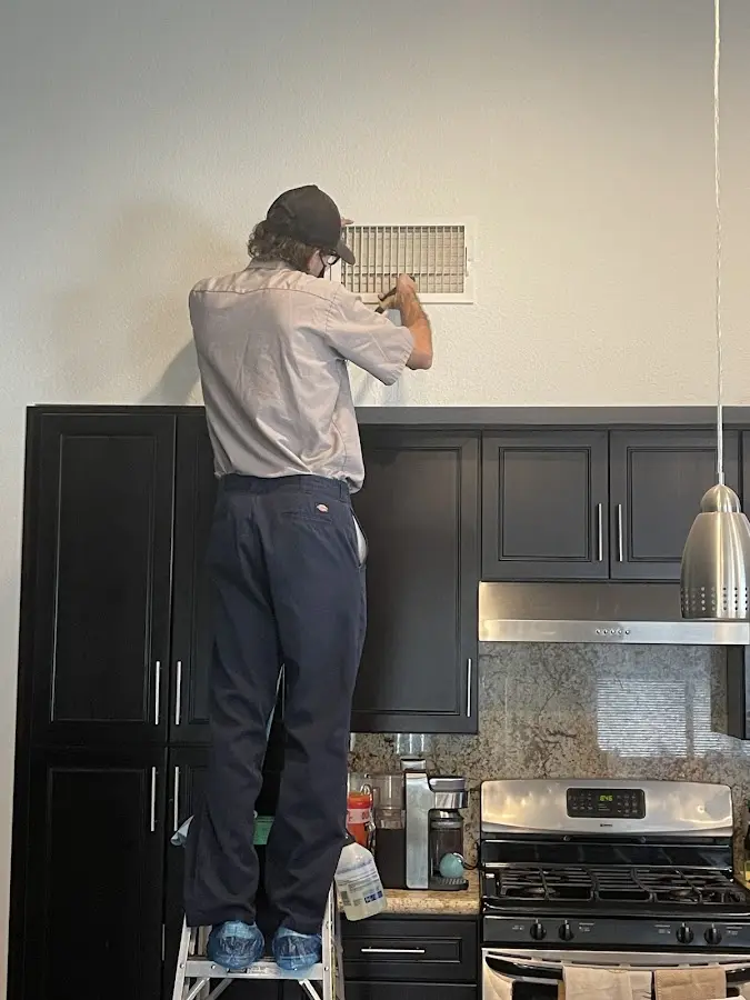 Technician inspecting an air vent during HVAC service in Chesterland